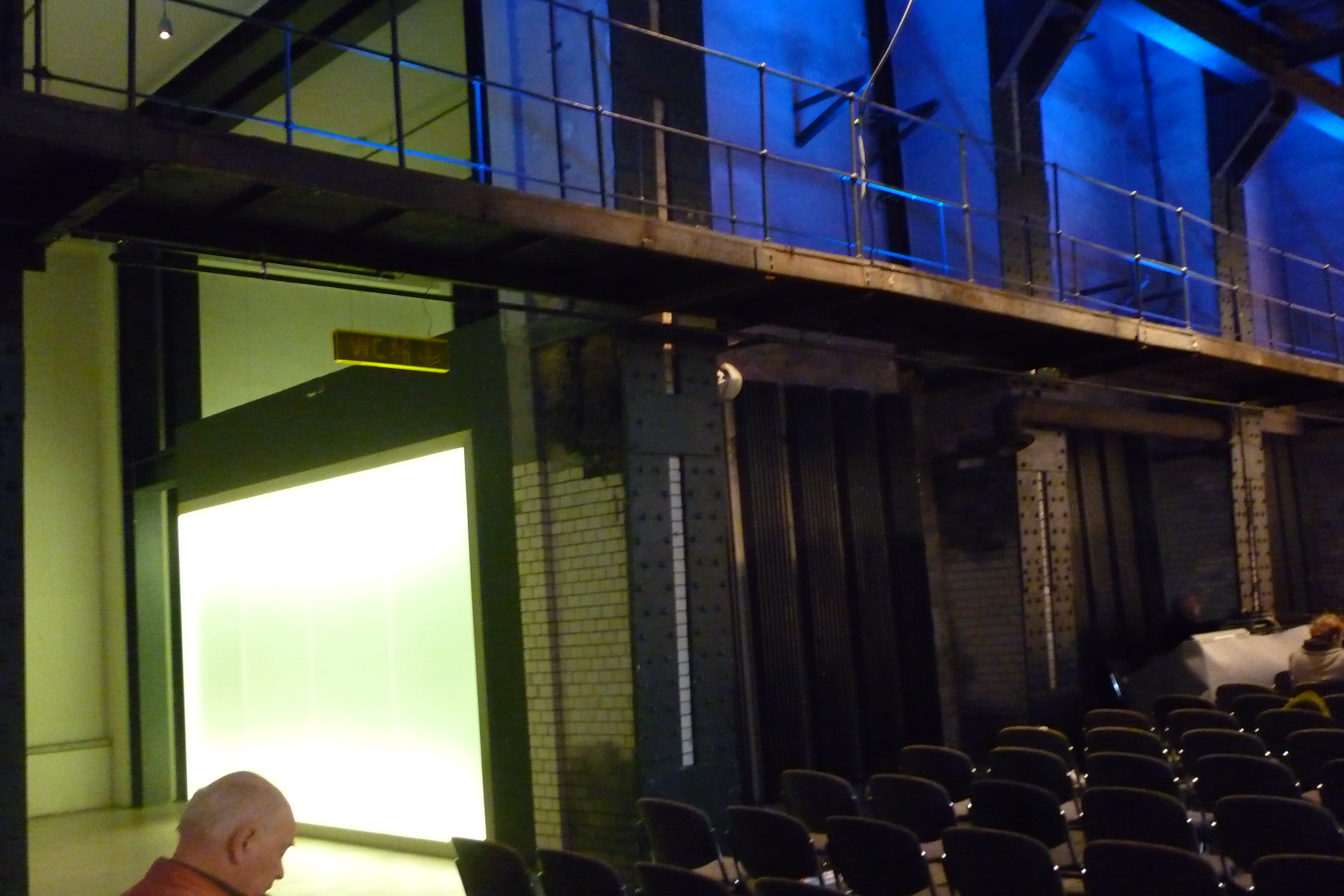 E -Werk, plenáris ülés csarnoka, kivilágított üvegfal mögött mosdó